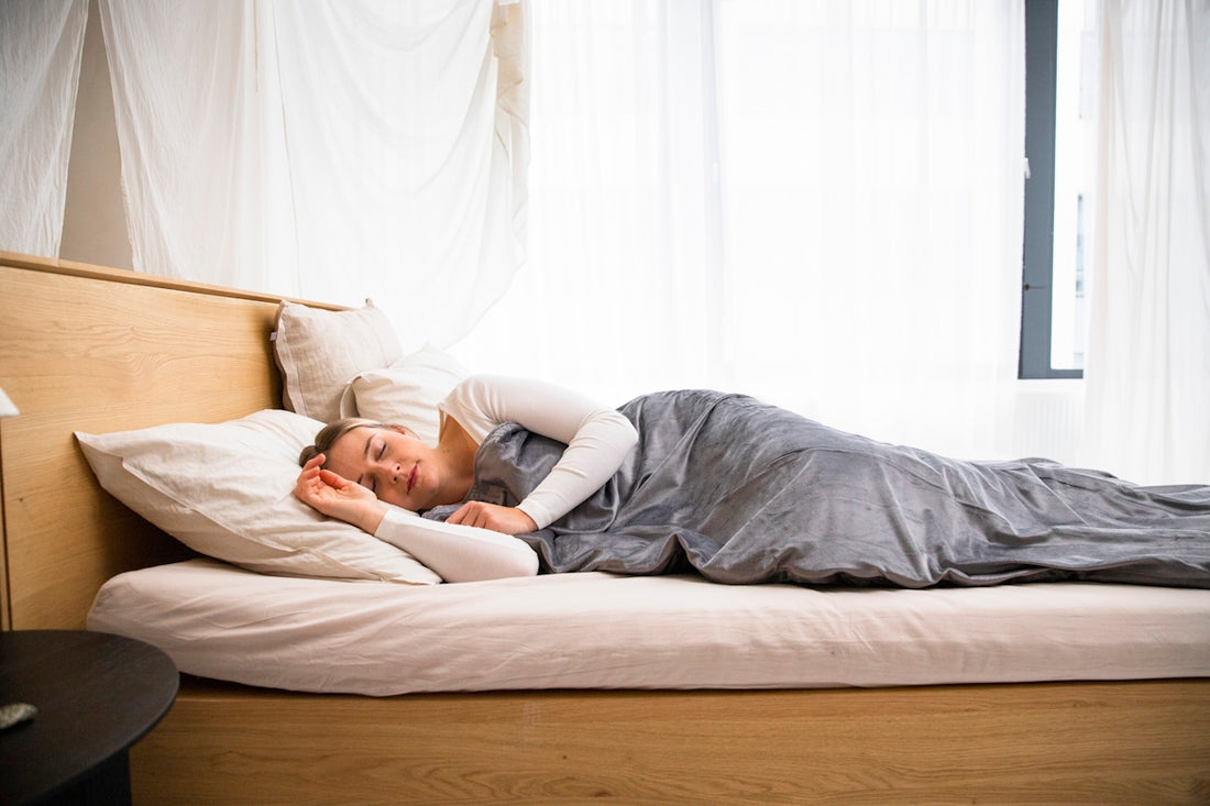 a man laying on a bed with a blanket on top of it