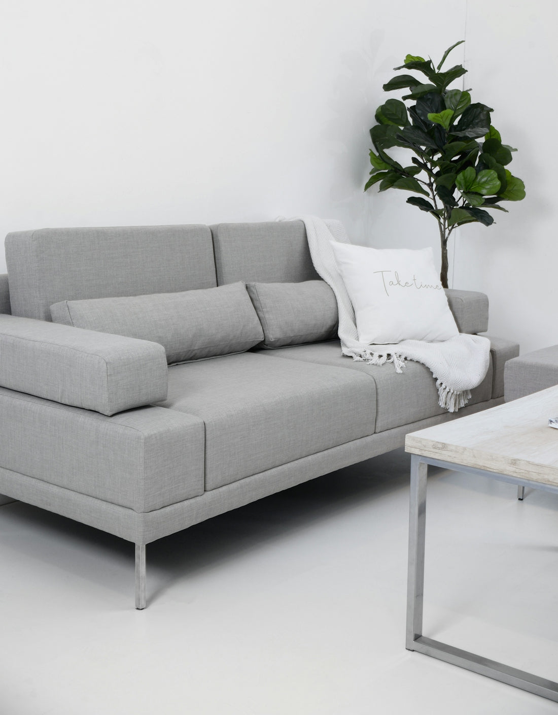 Modern gray sofa with throw blanket and pillow.