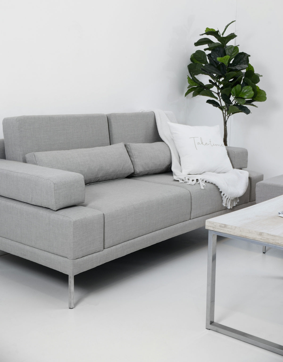 Modern gray sofa with throw blanket and pillow.