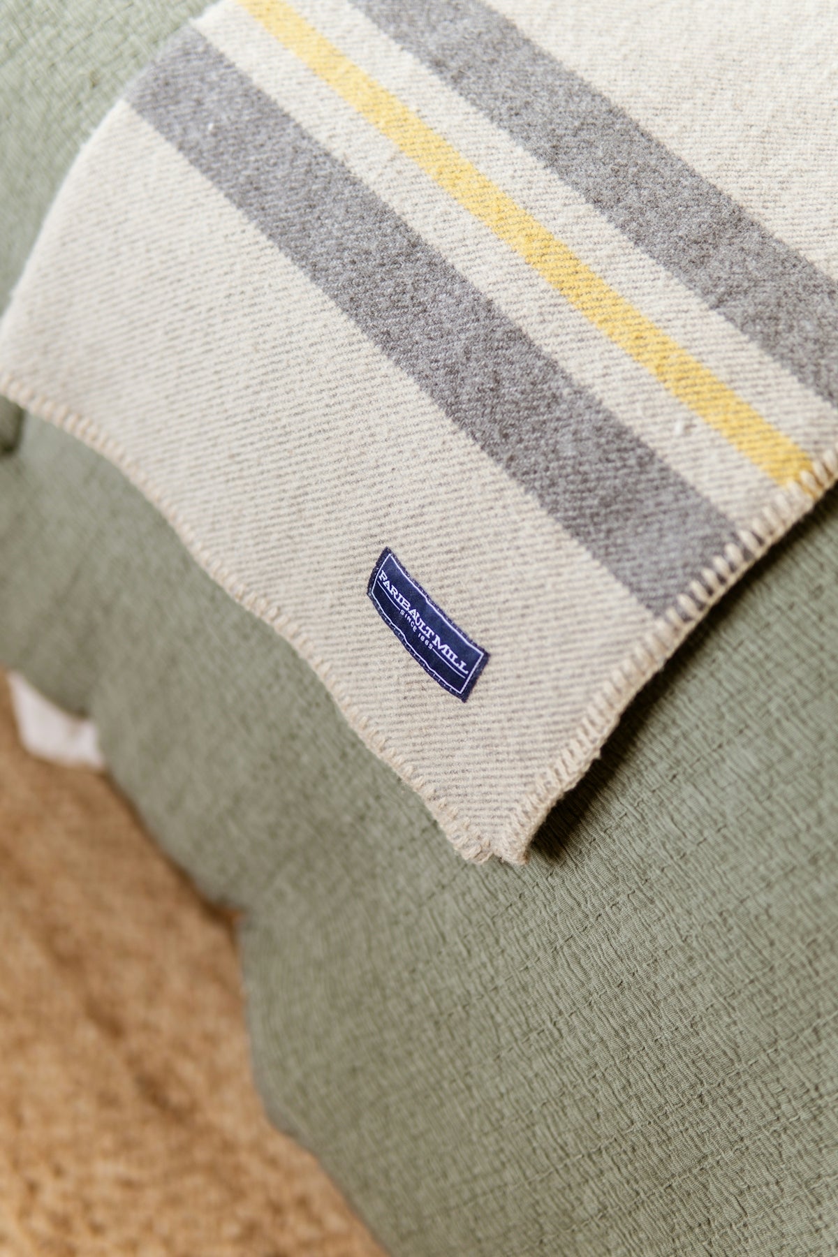 Striped blanket with blue label on a green textured surface.